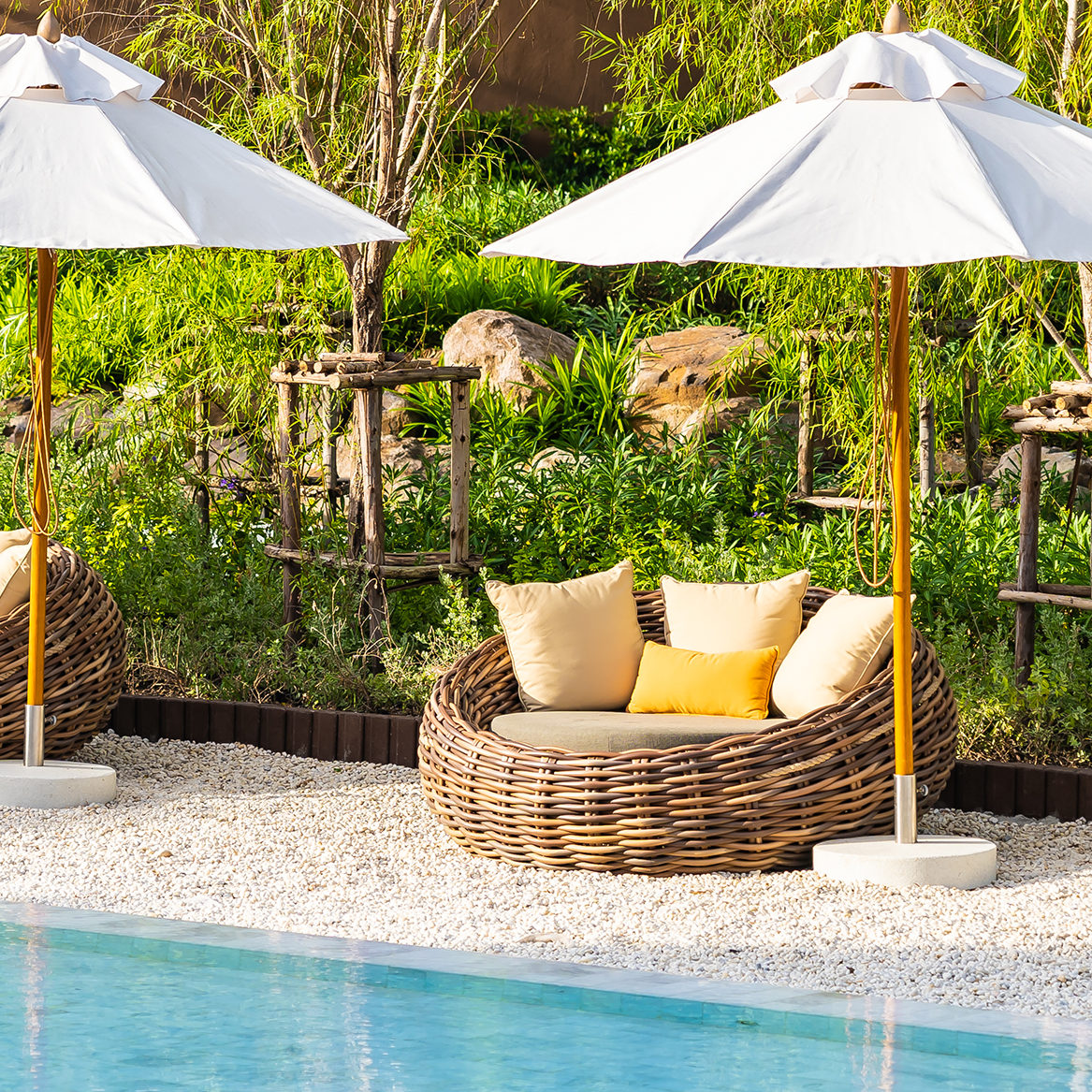 Umbrella and deck chair around outdoor swimming pool